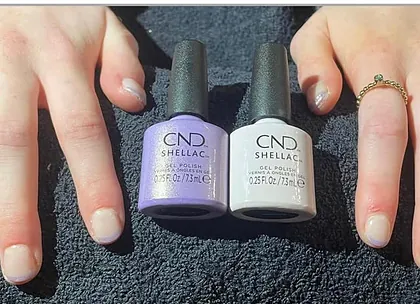 Nagels met CND Shellac in lila en wit, de twee flesjes ernaast